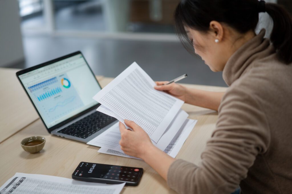 Woman analyzing financial documents and laptop