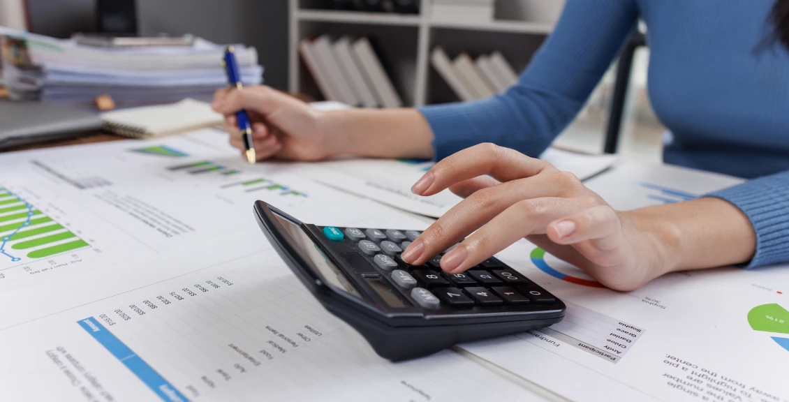 Hand holding pen near business charts